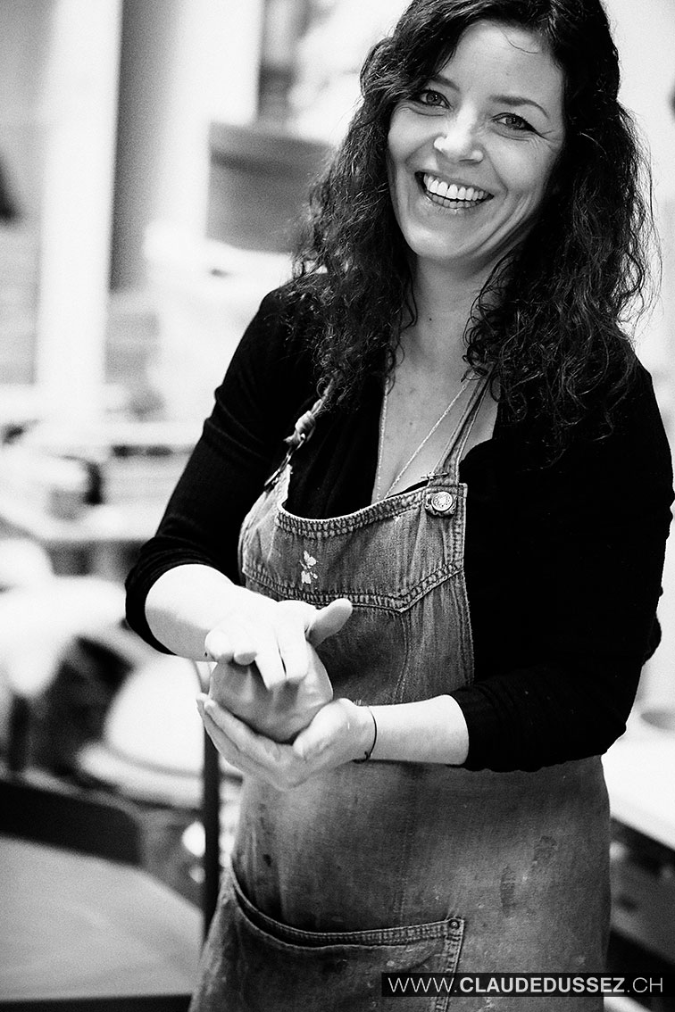 Portrait de Mathilde Roux, souriante, en tablier de travail dans son atelier.