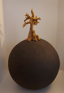 Sculpture en grès, un arbre doré posé sur une sphère sombre.