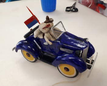 Petite voiture bleue en céramique avec un personnage.
